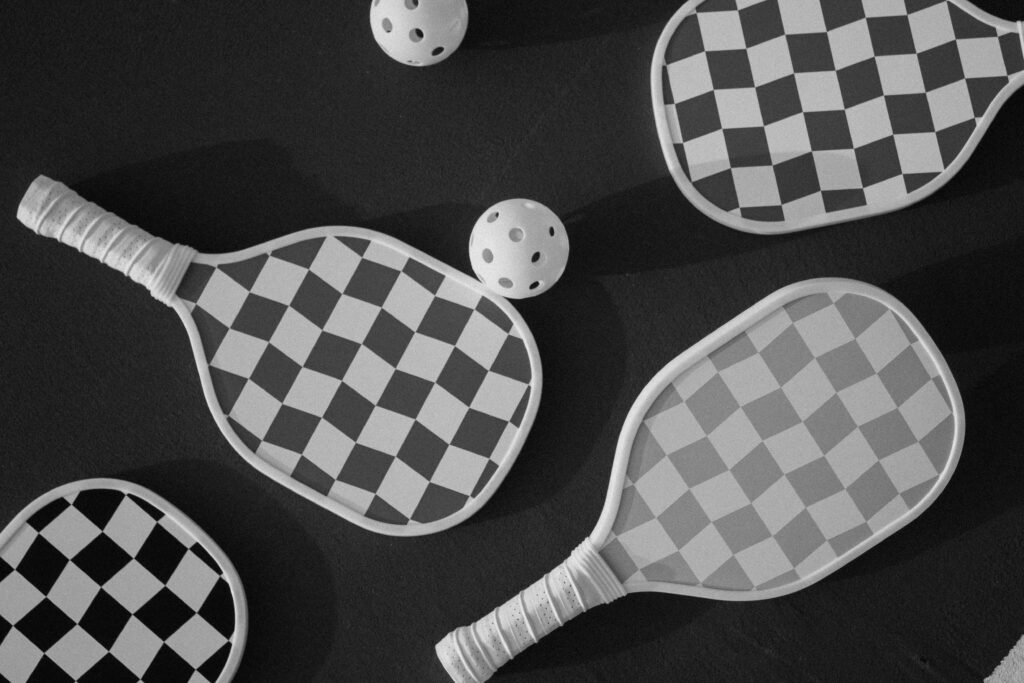 Top view of checkered paddles and balls on a dark surface, perfect for sports themes.