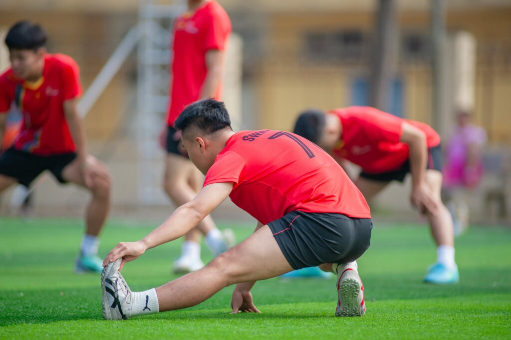 Young athletes stretch before a soccer game in Hanoi, showcasing teamwork and fitness.