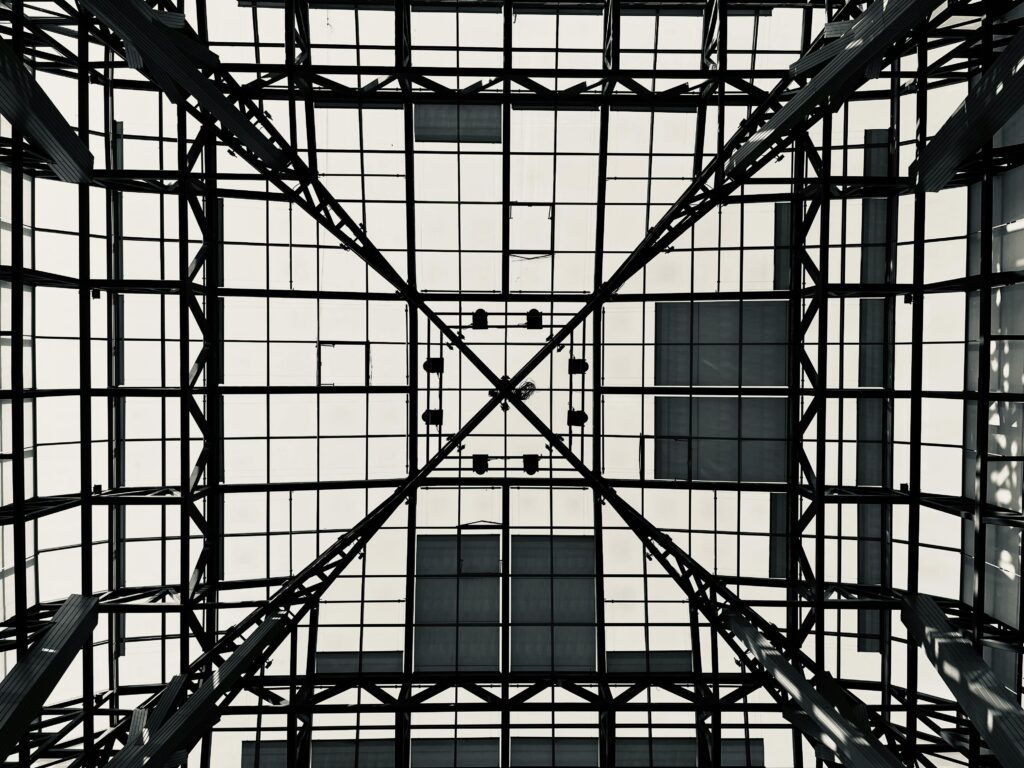 Black and white geometric pattern of a steel and glass ceiling viewed from below.