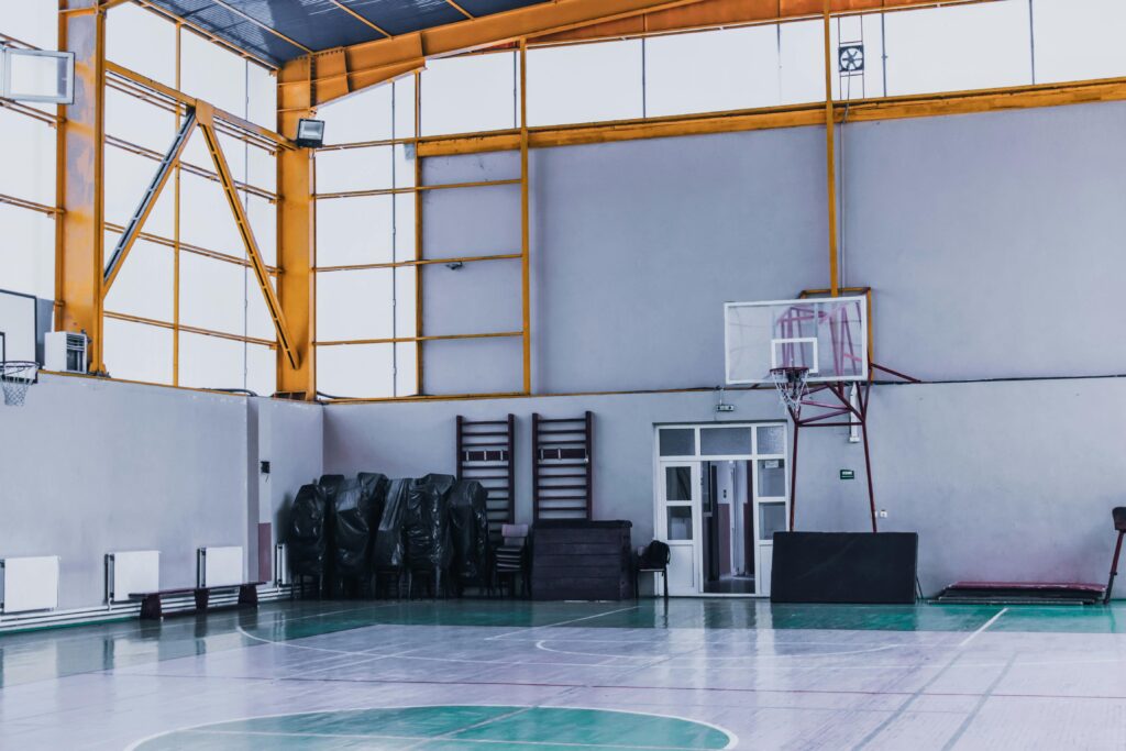 Modern empty sports hall with basketball hoop and various fitness equipment in daytime