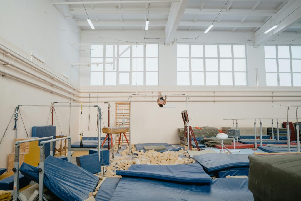 Bright indoor gymnastics facility with various equipment and an athlete training.
