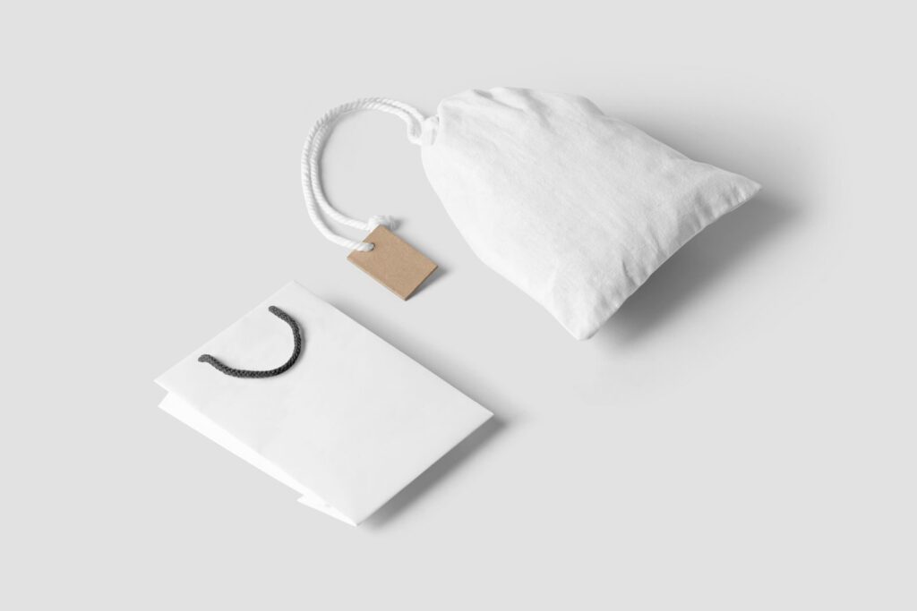 Elegant minimalist mockup featuring a white paper and cloth bag on a neutral background.