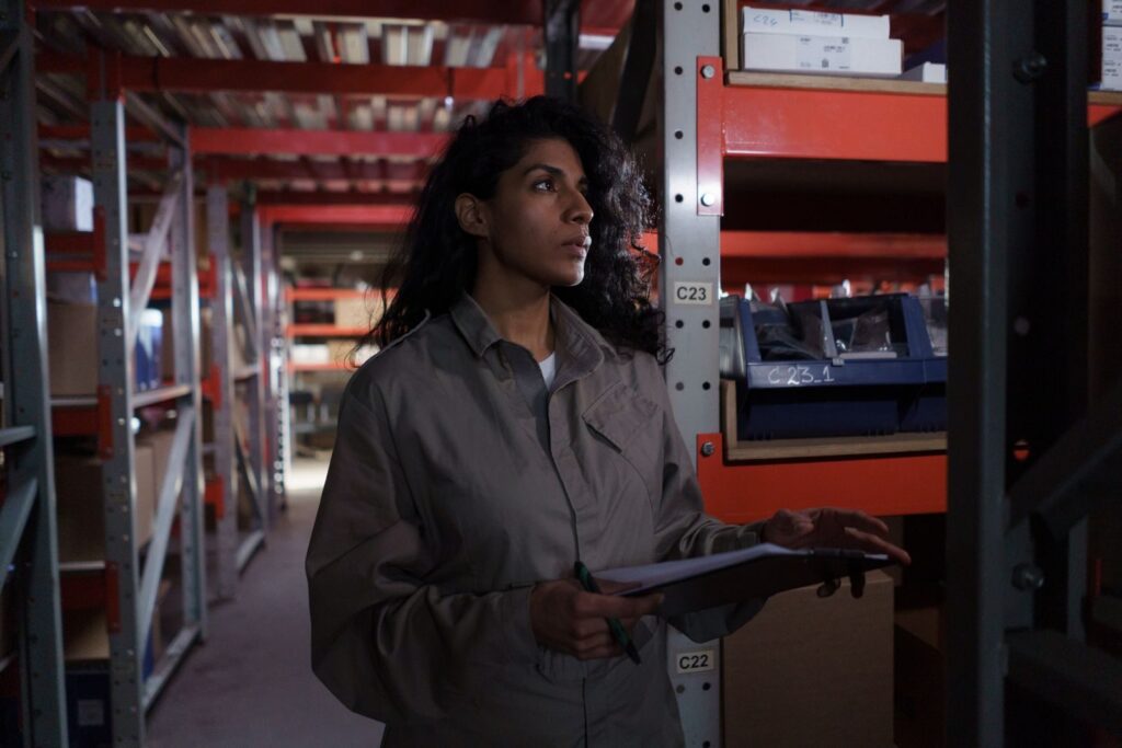 Female warehouse worker checking inventory in an industrial storage facility.