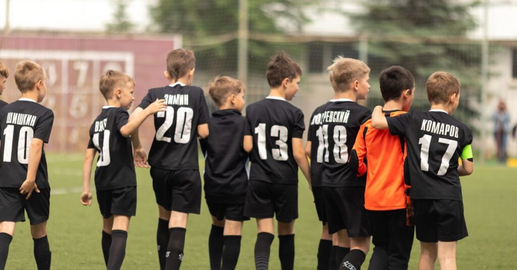 A group of young soccer players celebrating victory on the football field.