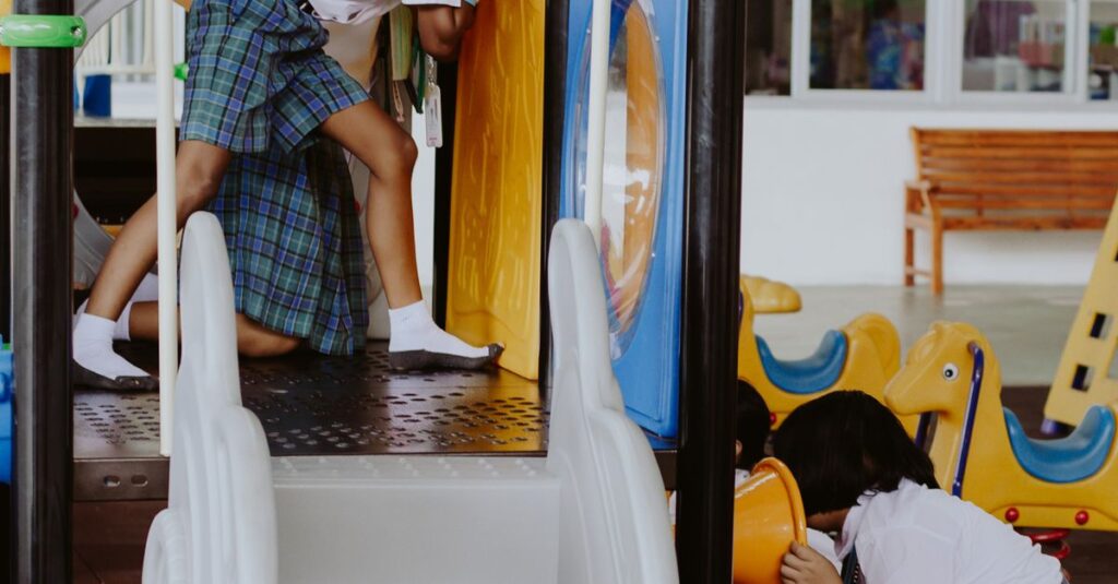 Kids in uniforms enjoying playtime on indoor playground at a school gymnasium.