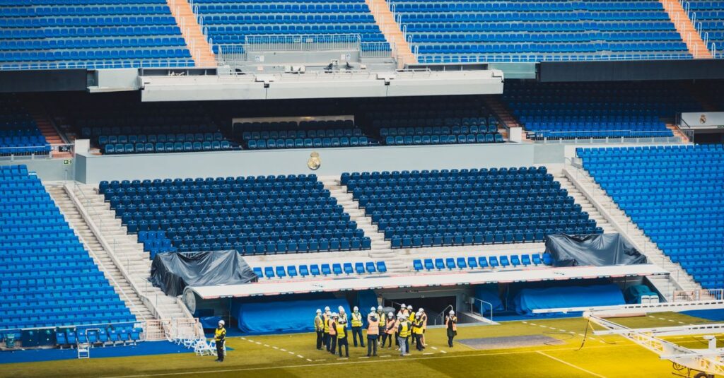 A wide-angle view of a stadium seating area in Madrid with visible workers and vibrant blue seats.