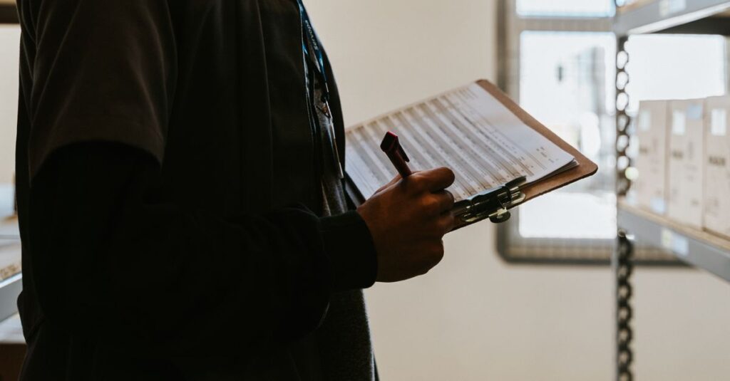 Industrial worker managing inventory in a warehouse with a clipboard and checklist.