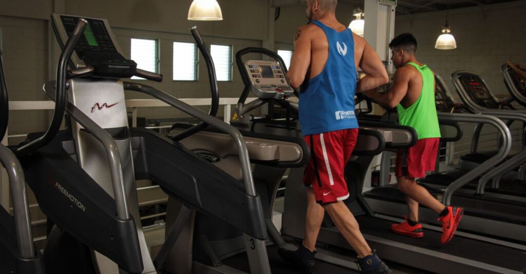 Two men running on treadmills in a modern gym, promoting fitness and health.