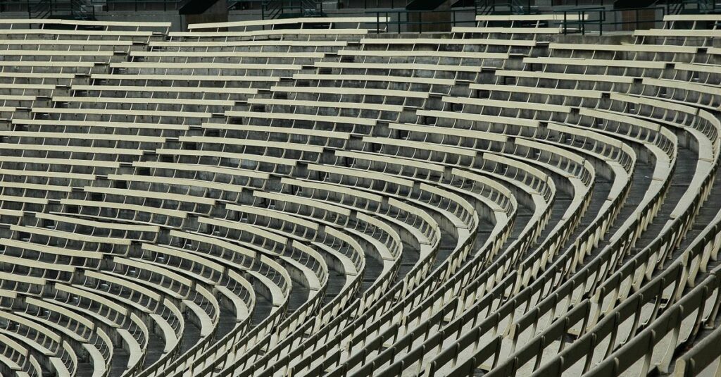 Wide angle view of empty stadium bleachers with a geometric pattern, showcasing rows of seats in a sports venue.