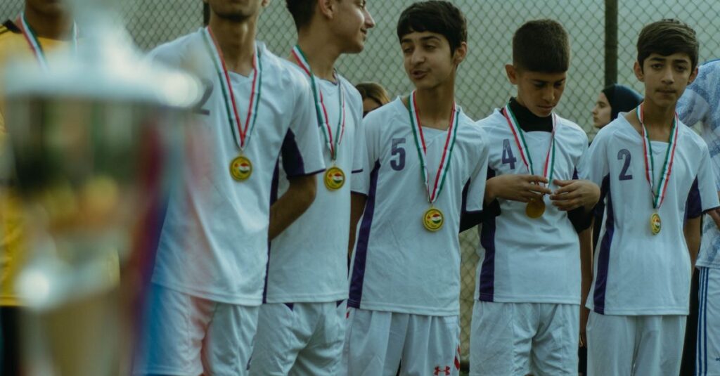 Teenage soccer team in Erbil celebrating victory with medals on outdoor field.