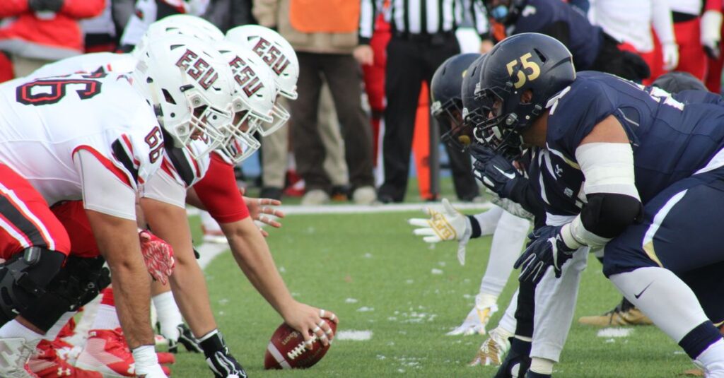 Rival football teams face off at the start of an action-packed game on the field.