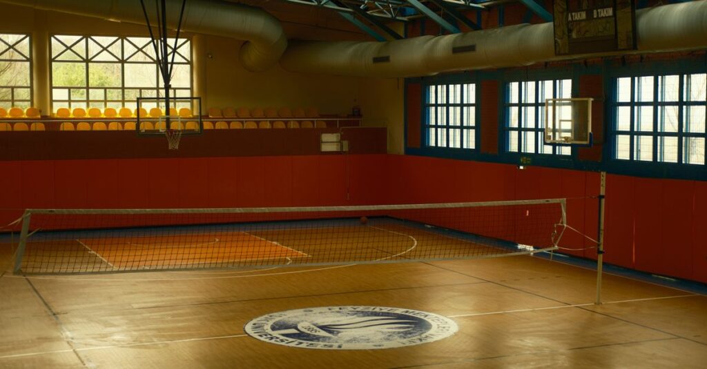 Spacious gym with volleyball net and basketball hoop, ideal for sports activities.