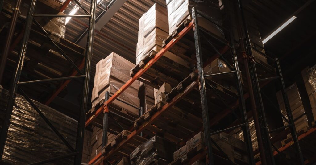 Interior view of a warehouse with stacked cardboard boxes on high shelves, showcasing storage and logistics.