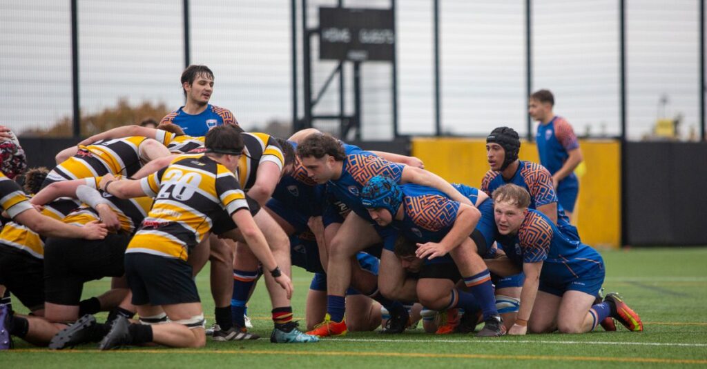 University rugby teams engage in a scrum during a competitive outdoor match.