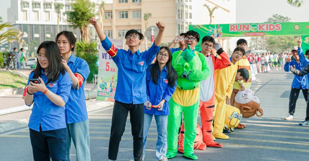 A lively scene of teenagers at a fun run event outdoors, with colorful costumes and cheerful expressions.