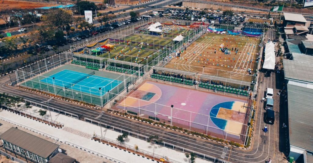 Aerial shot of colorful sports complex with tennis, basketball courts, and running tracks.