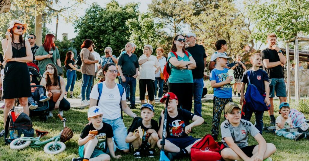 A diverse group of people enjoying a sunny day at an outdoor community event in a park setting.