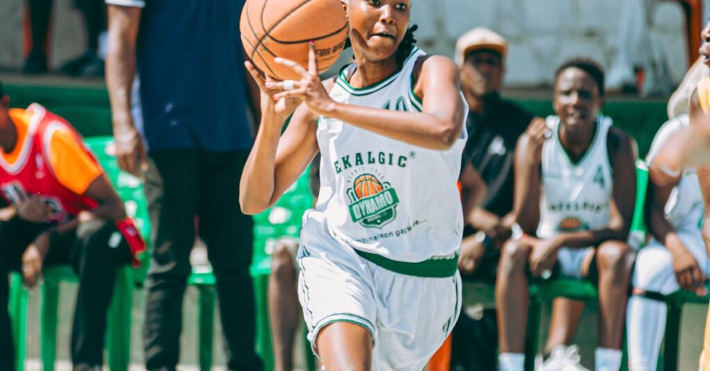 Energetic female basketball player dribbling during a game outdoors.