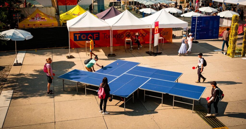 People enjoying a game of ping pong at the vibrant Toronto Outdoor Art Fair.