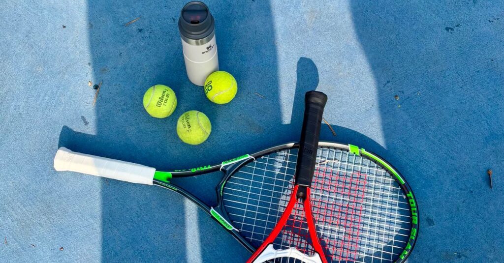 Tennis rackets and balls on a court under sunlight, ideal for sports themes.