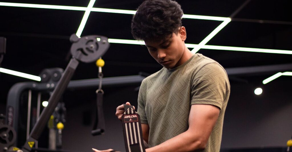 South Asian man adjusts wrist wraps in a modern gym. Focus on fitness and preparation.