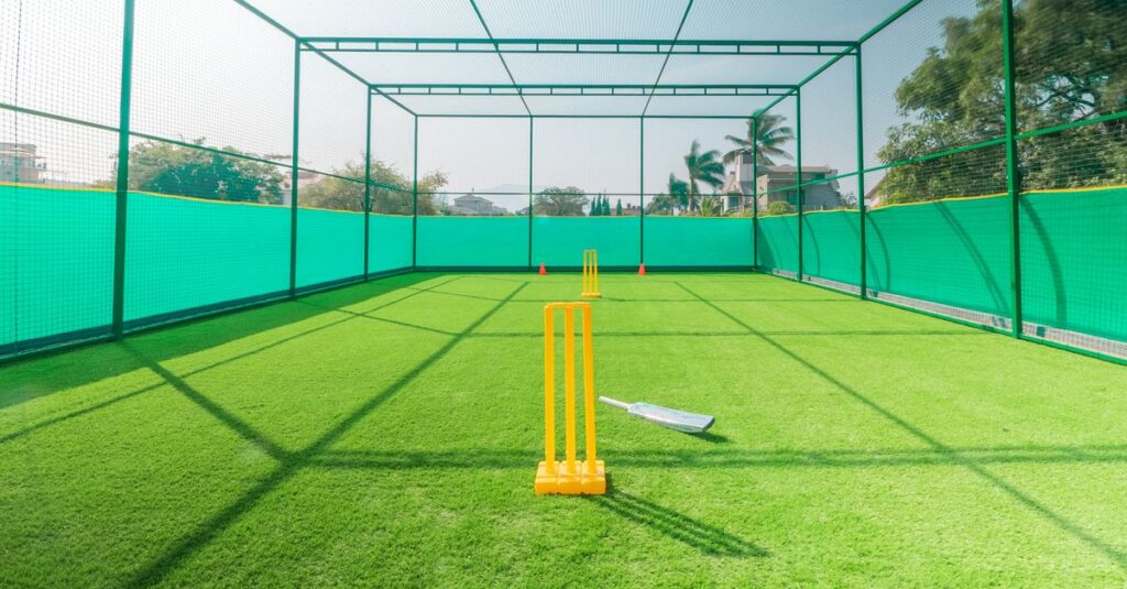 A cricket practice net with bright yellow stumps on a sunny day, ideal for training.