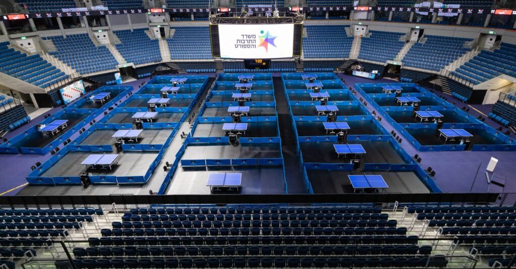 Aerial view of a large arena set up for a table tennis tournament with multiple tables.