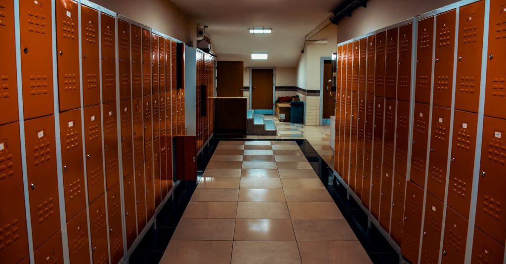 Vacant locker room with orange lockers and tiled flooring in a modern sports facility.