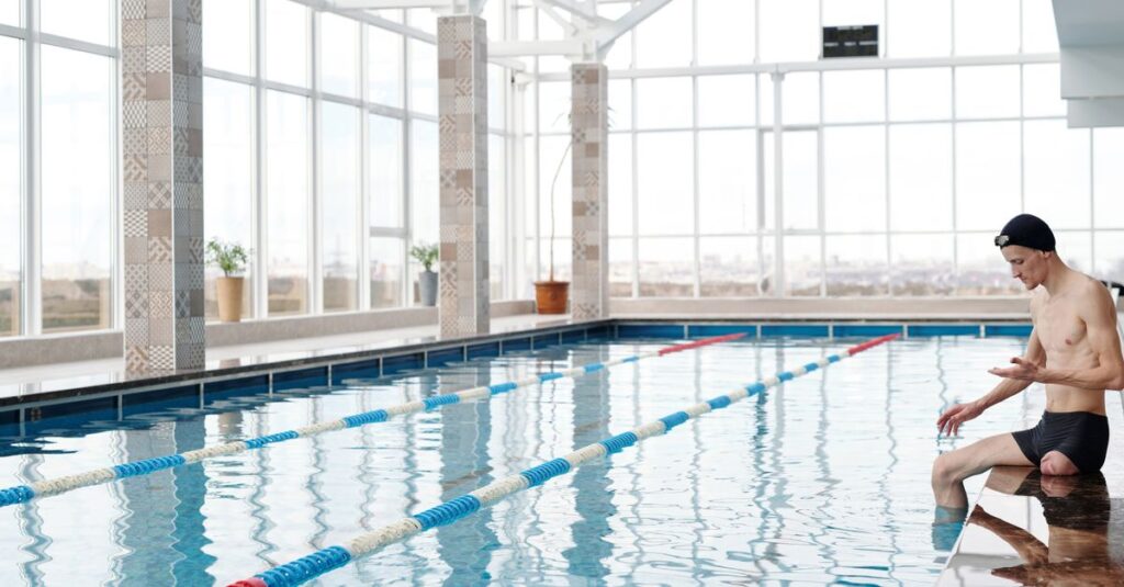 Young man sitting by an indoor swimming pool, preparing for a swim session, reflecting calm and focus.