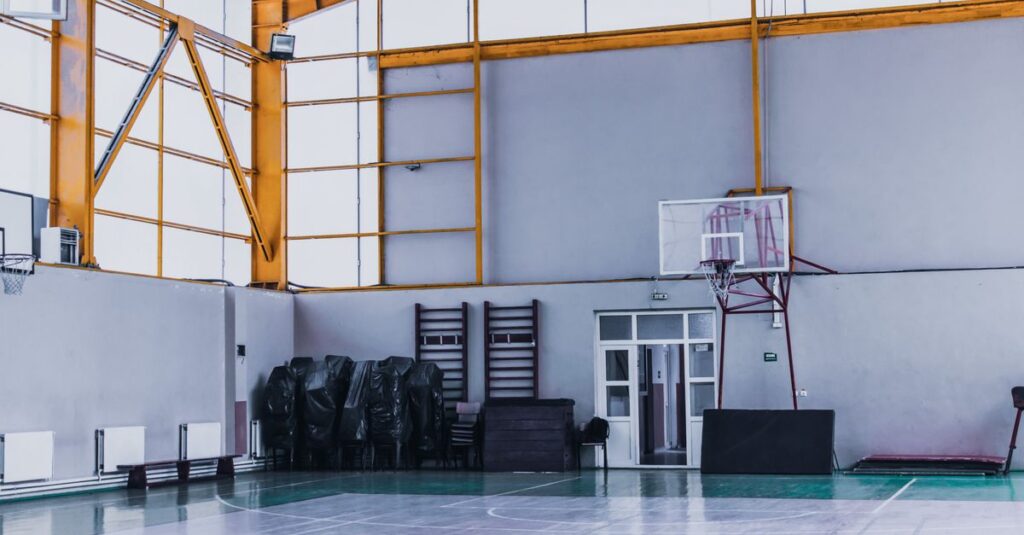 Modern empty sports hall with basketball hoop and various fitness equipment in daytime