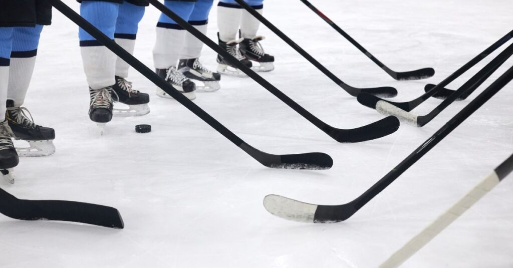 Close-up of hockey players on ice with sticks ready for a faceoff.
