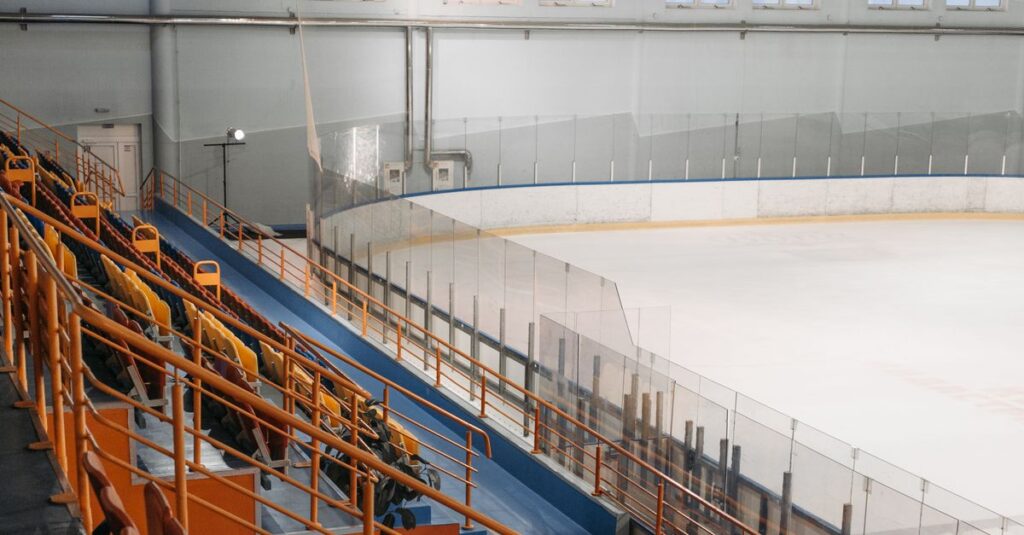 A spacious indoor ice rink with empty bleachers under bright lighting.