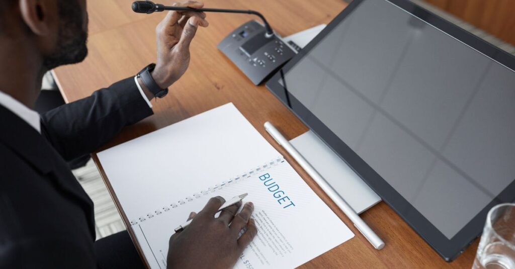 African American man in a meeting reviewing a budget document with a microphone