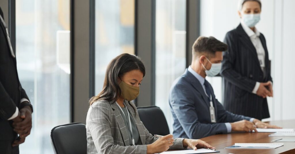 Professionals in face masks having a business meeting in a modern conference room.