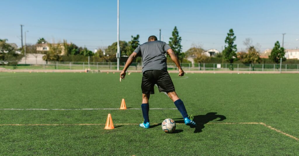 A soccer player practicing drills on a sunny day on an outdoor field.