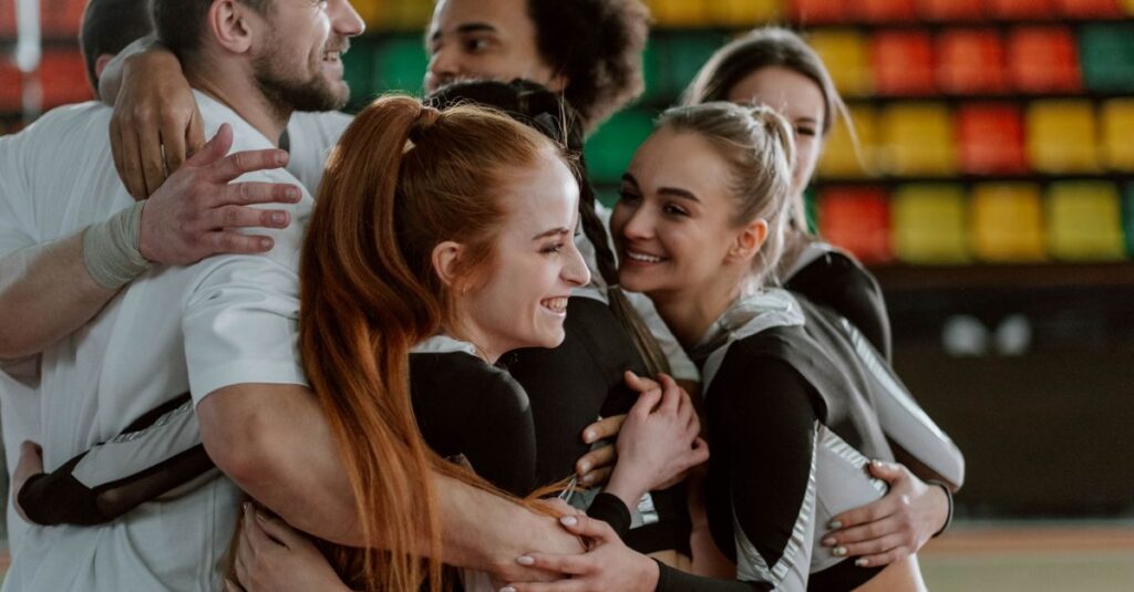 A joyful group of cheerleaders hugging, celebrating a successful performance indoors.