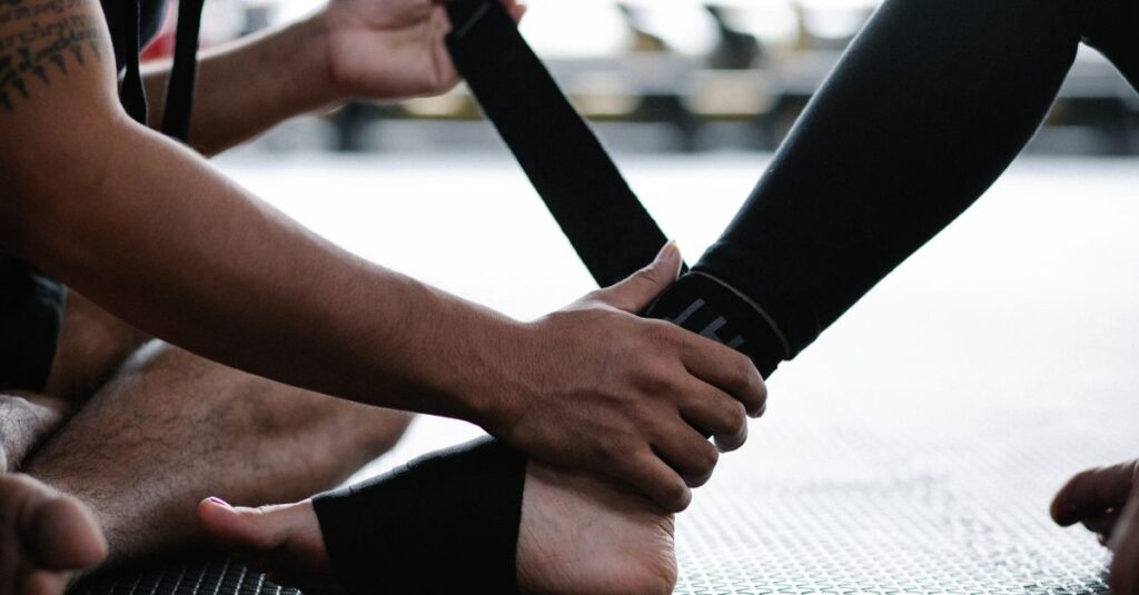 Close-up of an athlete's ankle being wrapped with an elastic bandage in a gym setting.
