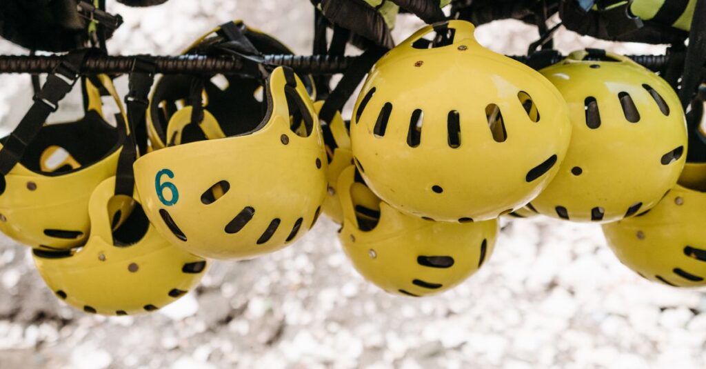 Cluster of yellow protective helmets hanging on a rack for outdoor activities like kayaking.