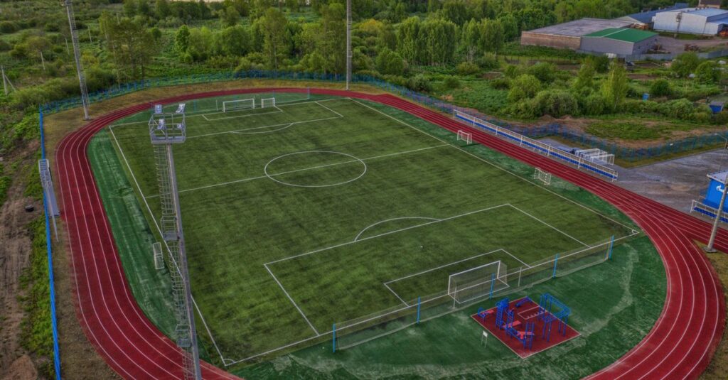 Aerial view of a vibrant sports complex including a football field and surrounding track.