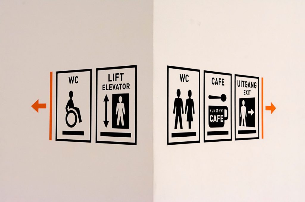 Close-up of wall signs including WC, elevator, cafe, and exit directions.