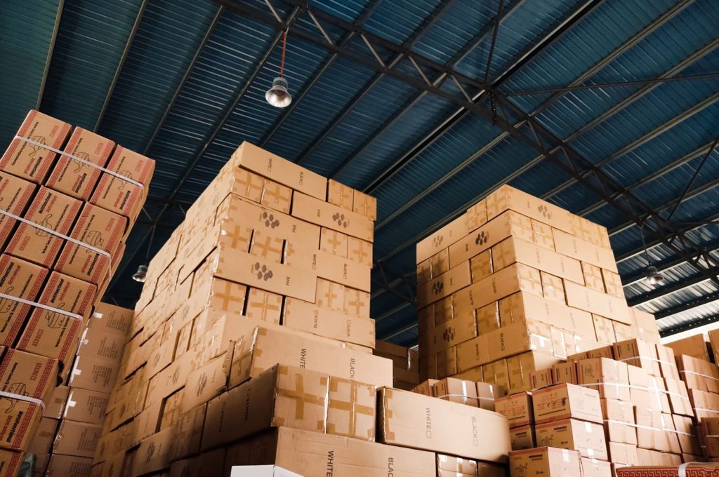 High stacks of cardboard boxes organized in a warehouse with a blue metal ceiling.