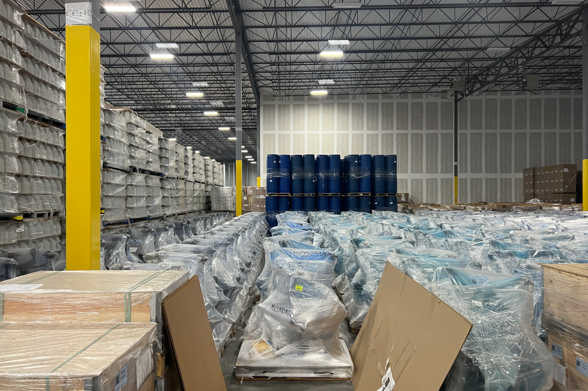 Large industrial warehouse filled with stacked goods wrapped in plastic for storage.