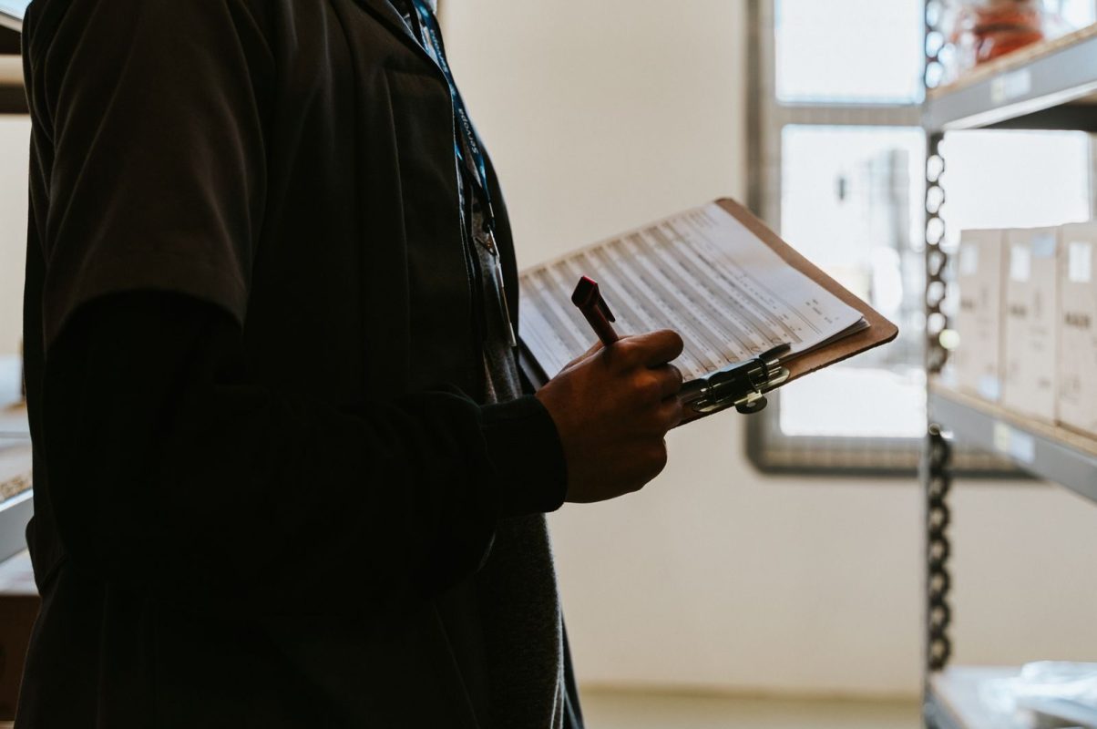 Industrial worker managing inventory in a warehouse with a clipboard and checklist.