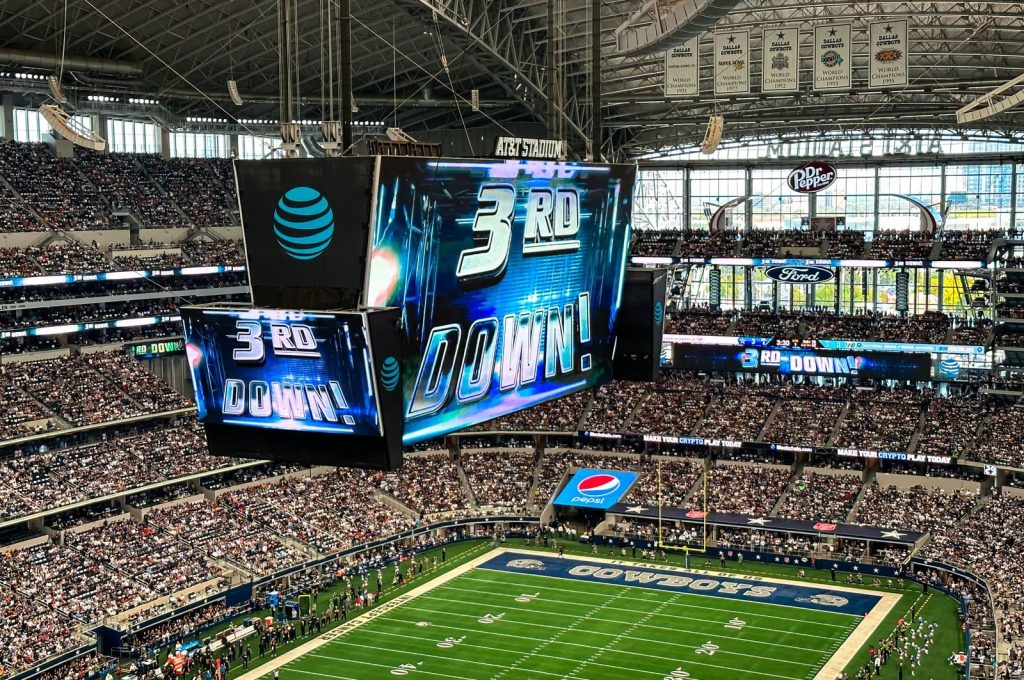 An exciting football game is underway at the AT&T Stadium in Arlington, Texas, with a packed crowd and dynamic atmosphere.