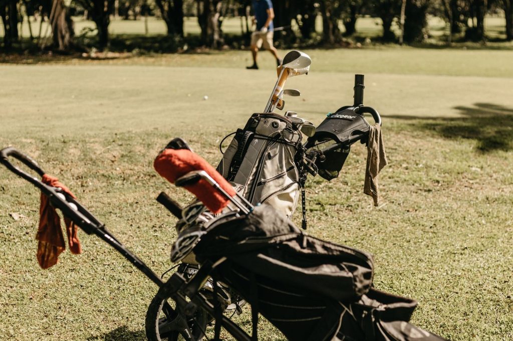 A golf bag and clubs on a sunny golf course, perfect for summer leisure.