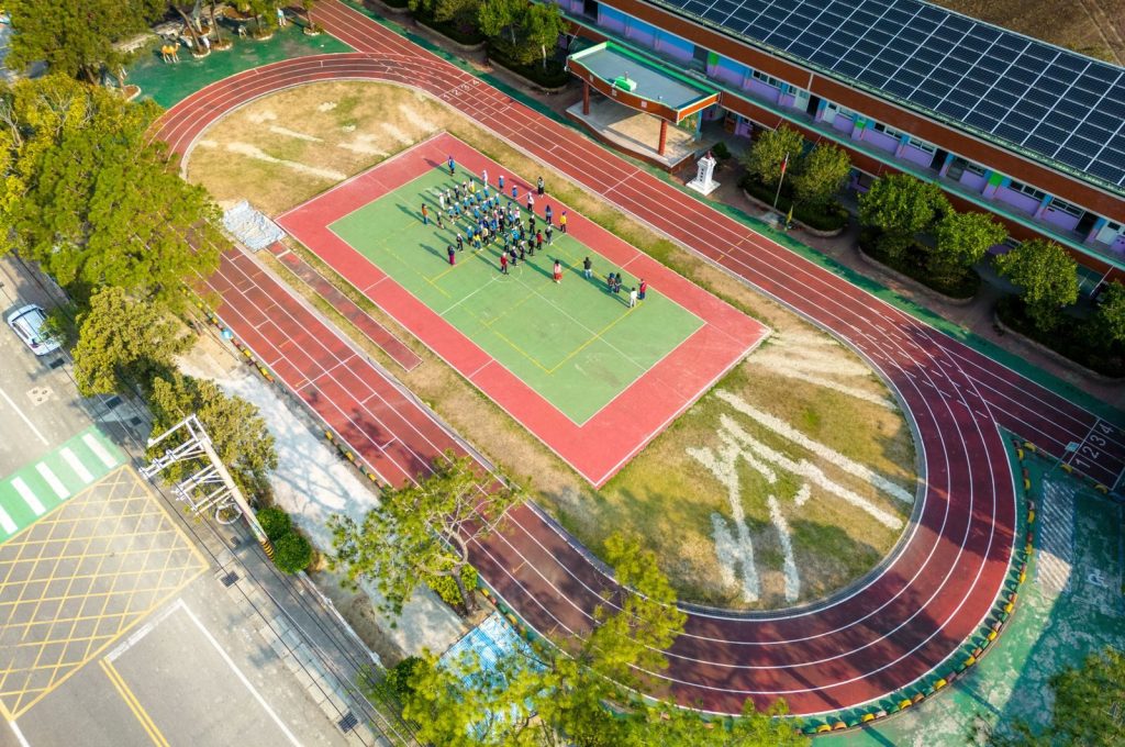 Aerial shot showcasing a school sports area with students on a court, surrounded by a running track.