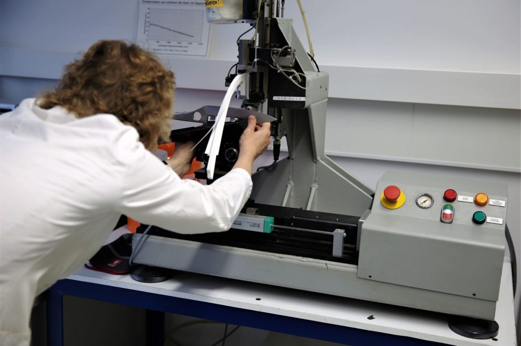 Scientist operates a precision testing machine in a modern laboratory setting.