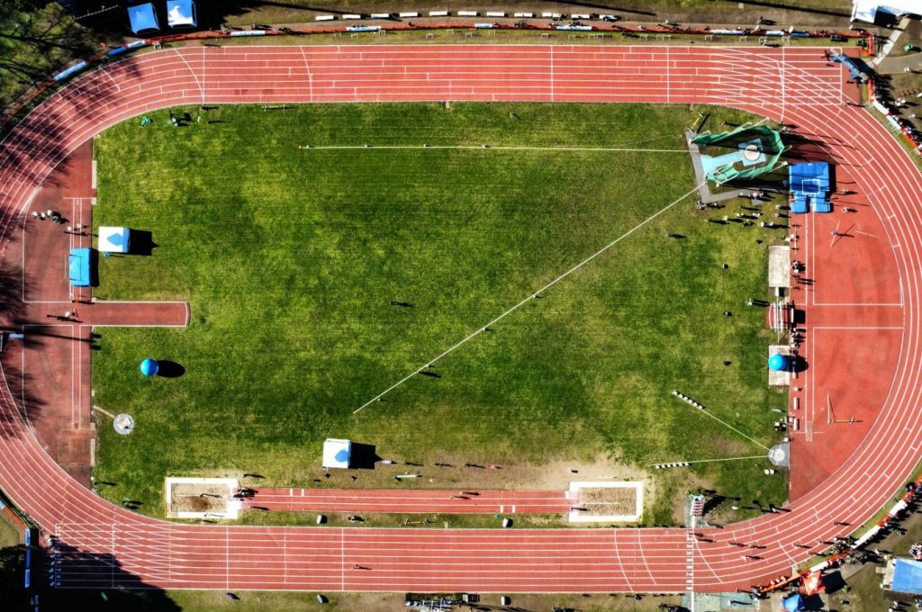Drone shot of an athletics stadium with red tracks and green field in Mar del Plata, Argentina.