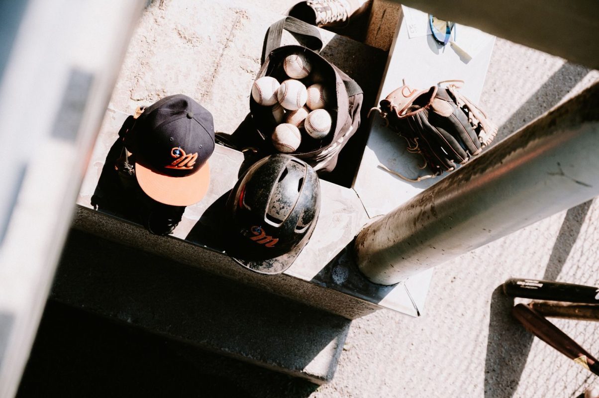 Top view of baseball gear including helmets, cap, gloves, and balls on the steps.