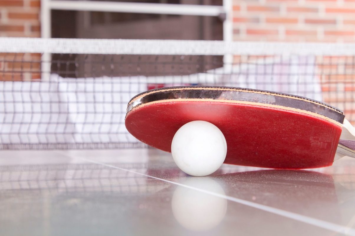Close-up shot of a table tennis paddle and ball on a table, capturing the essence of the sport.